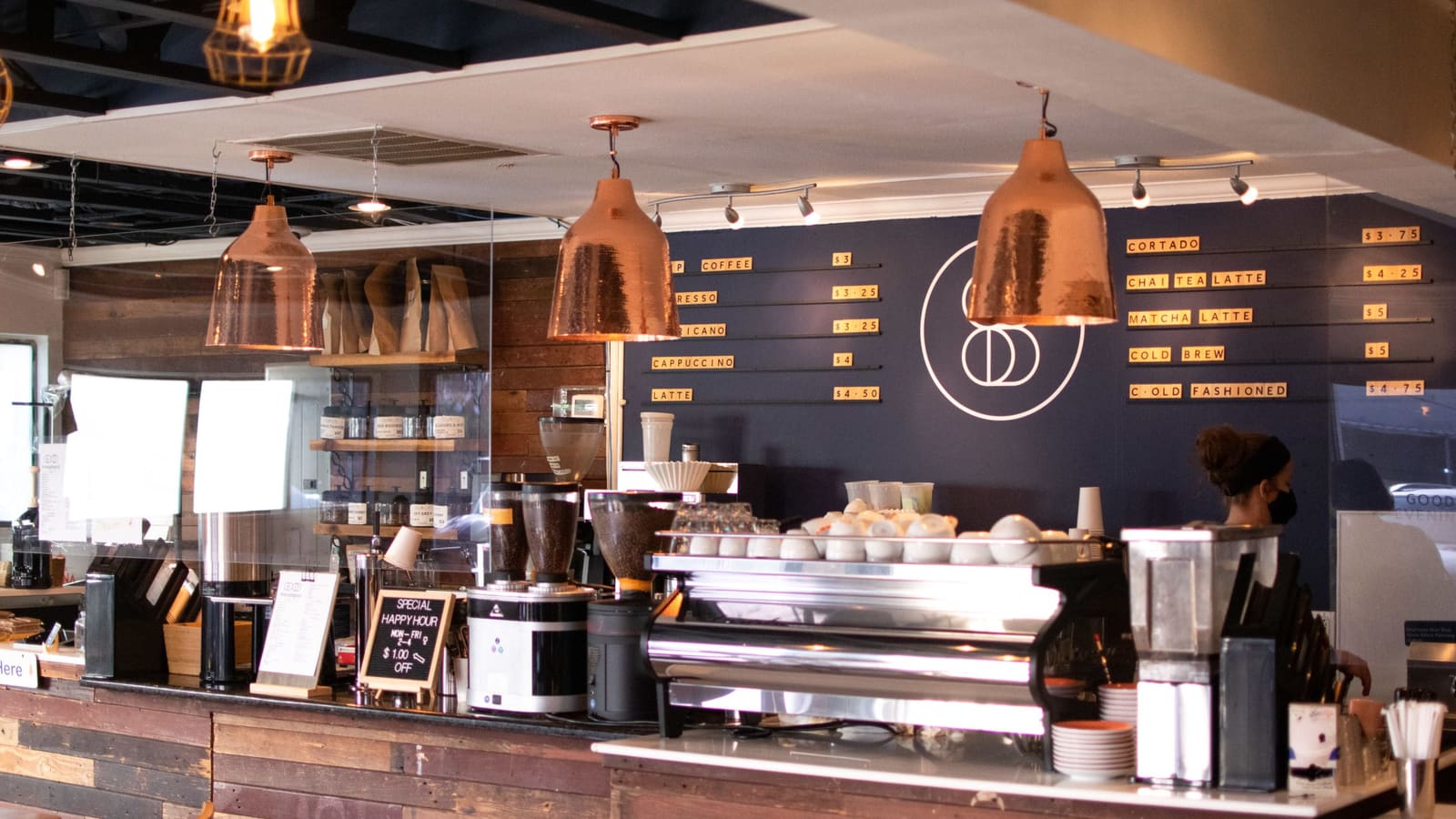 The counter at Café Sursock: copper lamps over the espresso machine, with the drinks board on the wall behind